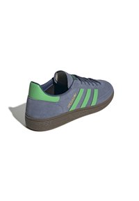 Zili zamšīgi sporta apavi ar zaļiem akcentiem un trim svītrām, ar brūnu teksturētu zoli un zelta "SPEZIAL" zīmolu sānos.