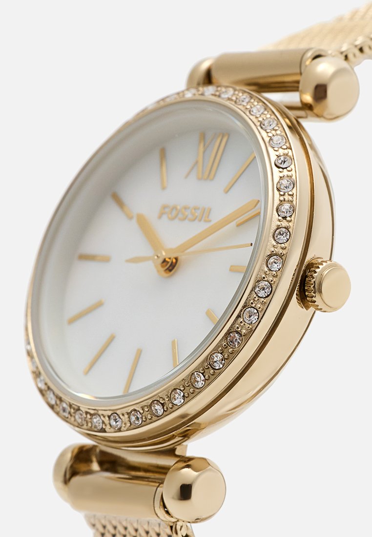Orologio Fossil in tono oro con quadrante bianco, indicatori in numeri romani e una lunetta decorata con cristalli. Presenta un bracciale a rete con chiusura sicura.