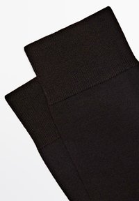 Czarne grube legginsy dziane z gładką teksturą i szerokim pasem w talii, charakteryzujące się jednolitym wzorem na całej powierzchni materiału.