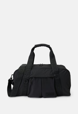 Sacs de sport en tissu noir avec poignées doubles, bandoulière ajustable avec le logo "HUGO", poche zippée à l'avant et un petit patch en relief.