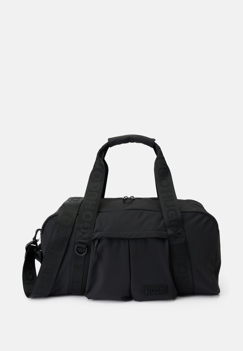 Bolsa de deporte negra de tela con asas dobles, correa de hombro ajustable con la marca "HUGO", bolsillo frontal con cremallera y un pequeño parche de logo en relieve.