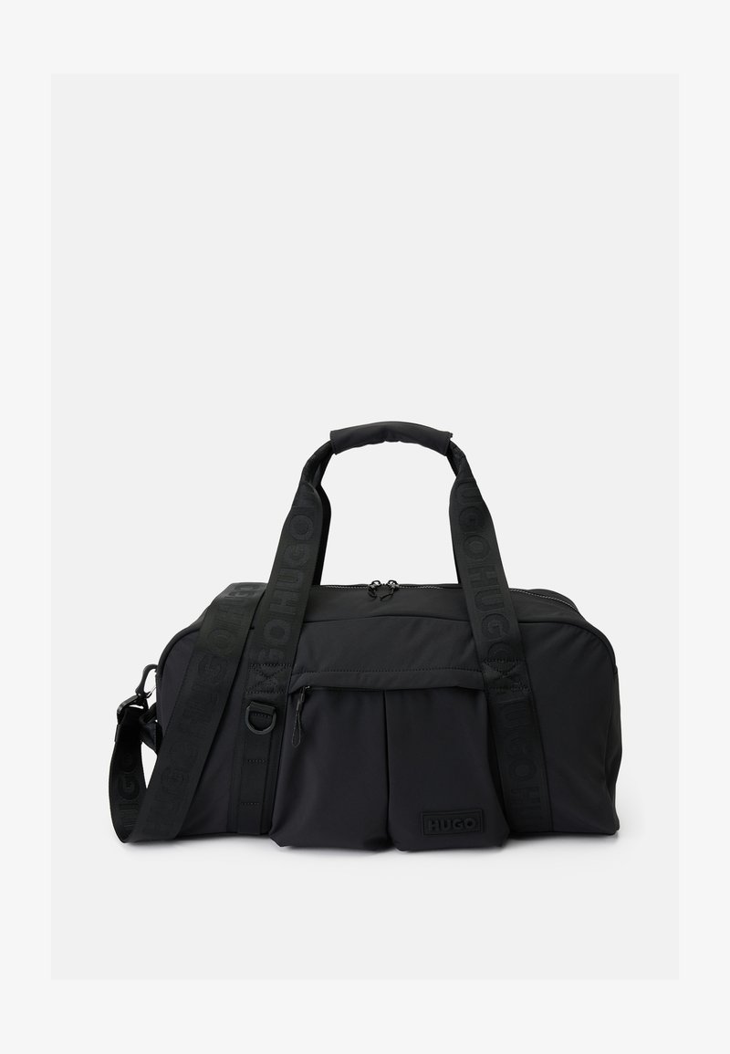 Bolsa de deporte negra de tela con asas dobles, correa de hombro ajustable con la marca "HUGO", bolsillo frontal con cremallera y un pequeño parche de logo en relieve.