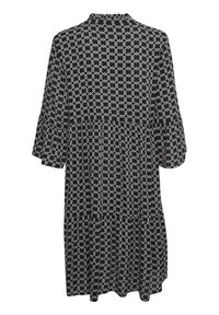 Vestido de patrón en blanco y negro con mangas acampanadas de tres cuartos, escote redondo, diseño en capas y una tela ligera.