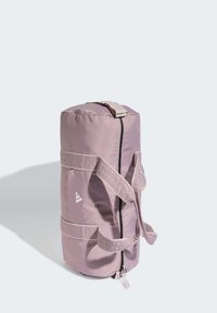 Στρογγυλή, μαλακή τσάντα duffel σε ανοιχτό λεβάντα ύφασμα με φερμουάρ, δύο ραμμένες λαβές και λογότυπο στο πλάι. Διακοσμητικά πάνελ με υφή.