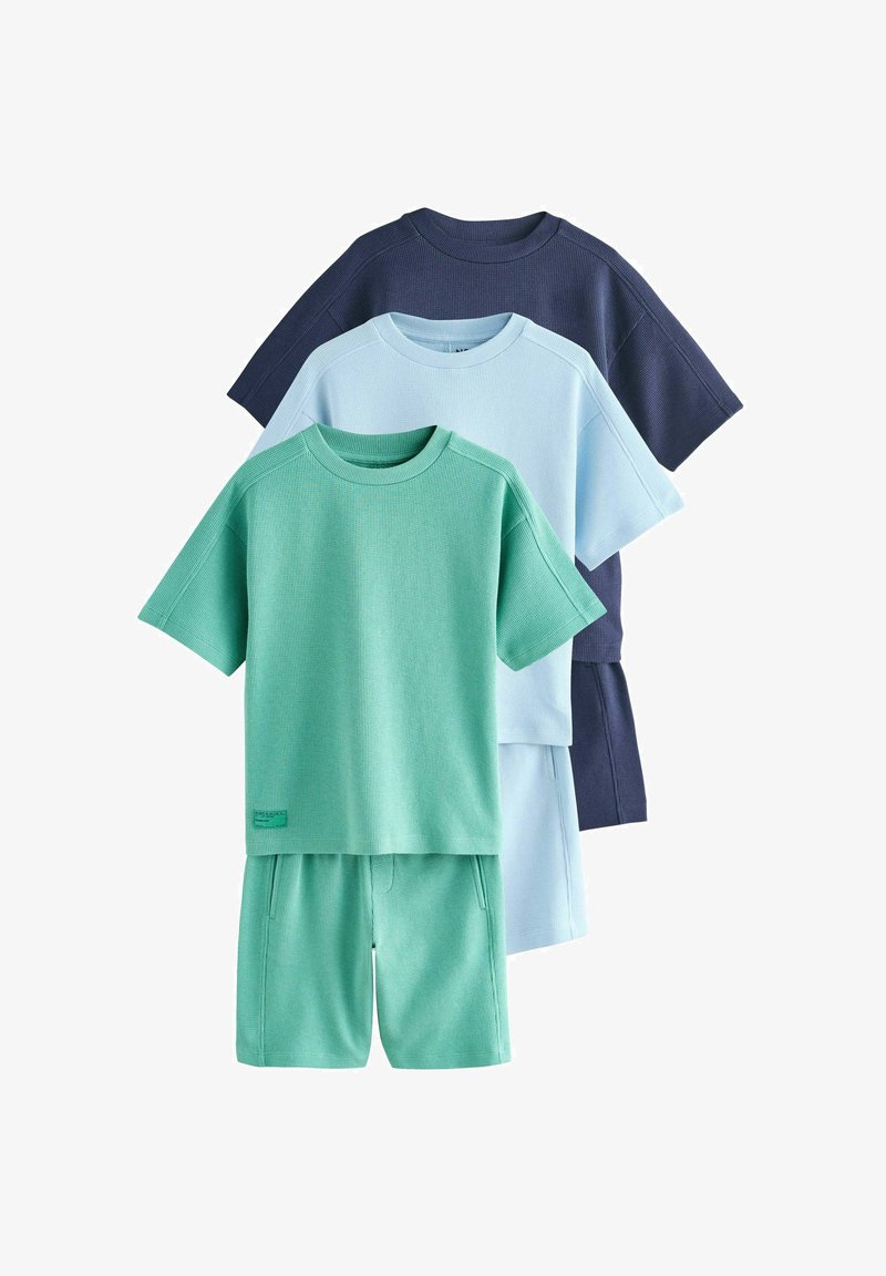 Tri súpravy tričiek s krátkym rukávom a šortiek v zelenej, svetlomodrej a tmavomodrej farbe s textúrovanou látkou, zobrazené vrstvené na bielom pozadí.