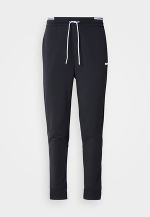 Schwarze Slim-Fit-Jogginghose mit weißem Kordelzug, elastischem Bund mit weißen Streifen und kleinem weißen Logo am oberen Oberschenkel.