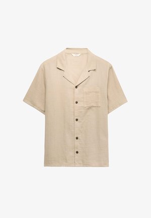 Camicia beige a maniche corte con bottoni, collo alla coreana e una tasca sul petto, su sfondo bianco.