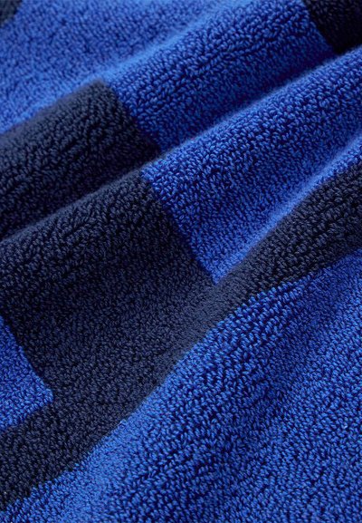 Μπλε και σκούρο ναυτικό ριγωτό ύφασμα από πετσέτα με ορατούς θηλιές και μαλακή υφή, εμφανιζόμενο σε κοντινές πτυχώσεις.