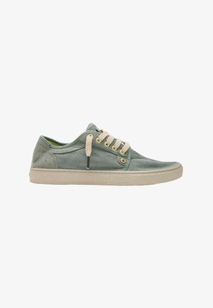 Zapatilla casual de caña baja en tejido verde apagado con cordones beige y una suela de goma beige claro con manchas, exhibida sobre un fondo blanco.