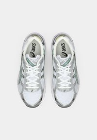 Valged spordijalatsid, millel on võrkmaterjal, hõbedased täiendused, rohelised detailid ja valged paelad. Omab pehmet tallatootlust mugavuse tagamiseks.