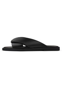 Infradito in pelle nera con design a fascia incrociata, suola piatta e texture liscia con un'estetica minimalista.
