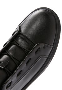 Zapatillas de cuero negro con punta redonda, diseño de cordones, superficie texturizada con acentos laterales y suela plana de goma.