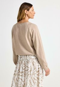 Beige zkrácený svetr s raglánovými rukávy, v kombinaci s lehkou bílou sukní se vzorem béžového zebřího tisku a smockovaným pasem.