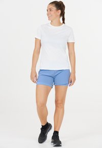 Weißes Sport-T-Shirt und hellblaue Shorts, beide aus leichtem Material. Schwarze Laufschuhe mit strukturierten Sohlen. Einfaches Design.