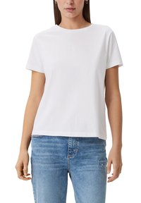 White cotton t-shirt with short sleeves, round neckline, slightly loose fit, featuring a subtle logo in the center. Paired with blue denim jeans.