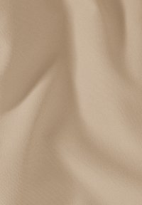 Tissu beige avec une texture lisse et mate, présentant des plis subtils et une couleur uniforme sans motifs ni accents.