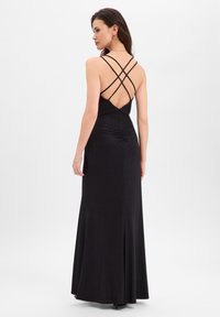 Robe de soirée noire au design ajusté, avec un dos froncé, un décolleté en V profond et des bretelles croisées. Texture lisse avec une légère brillance.