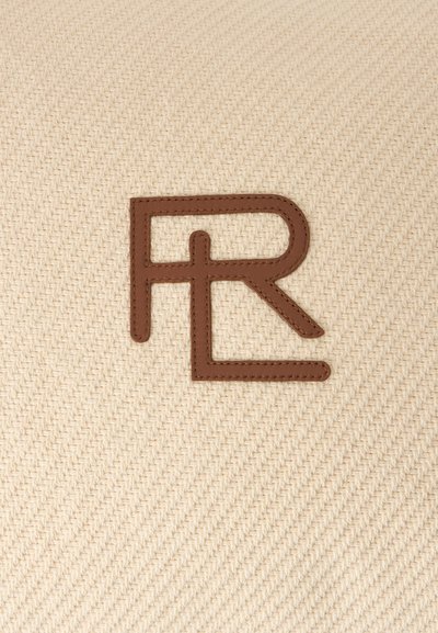 Monogramme en cuir marron cousu avec les lettres R et L qui se chevauchent sur un fond en tissu beige tissé.