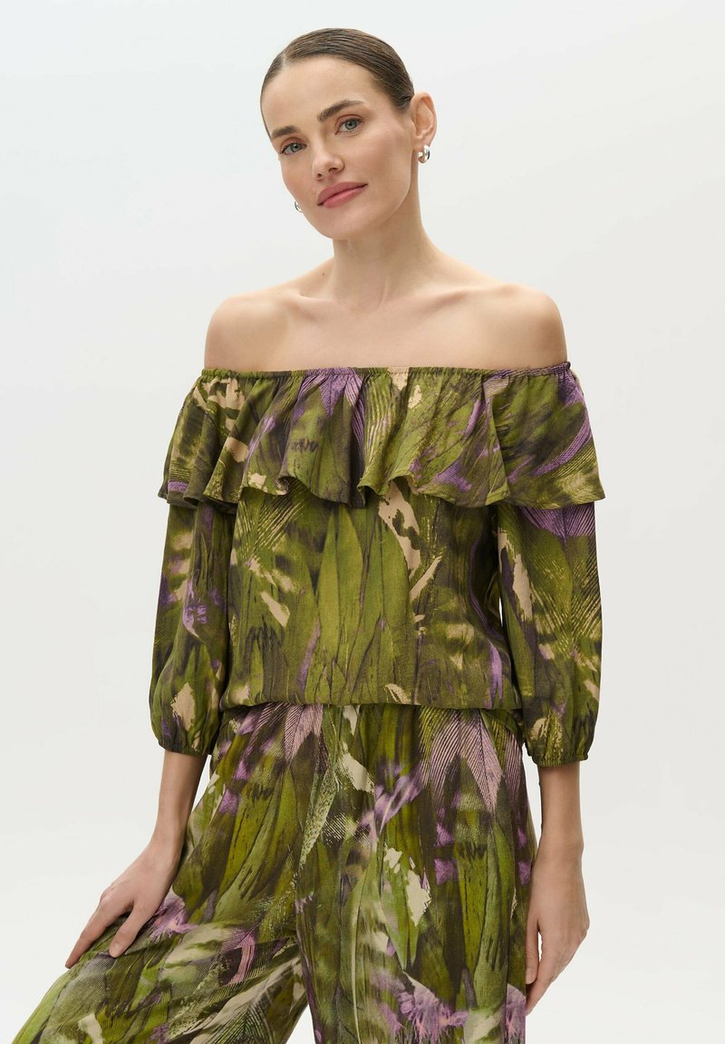 Blusa verde off-the-shoulder con patrón floral púrpura, detalles con volantes y puños elásticos. Tela ligera y fluida con un corte relajado.