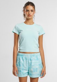Lys blå kort t-skjorte med korte ermer og en hvit trykt logo, kombinert med mønstrede lys blå shorts med elastisk linning.