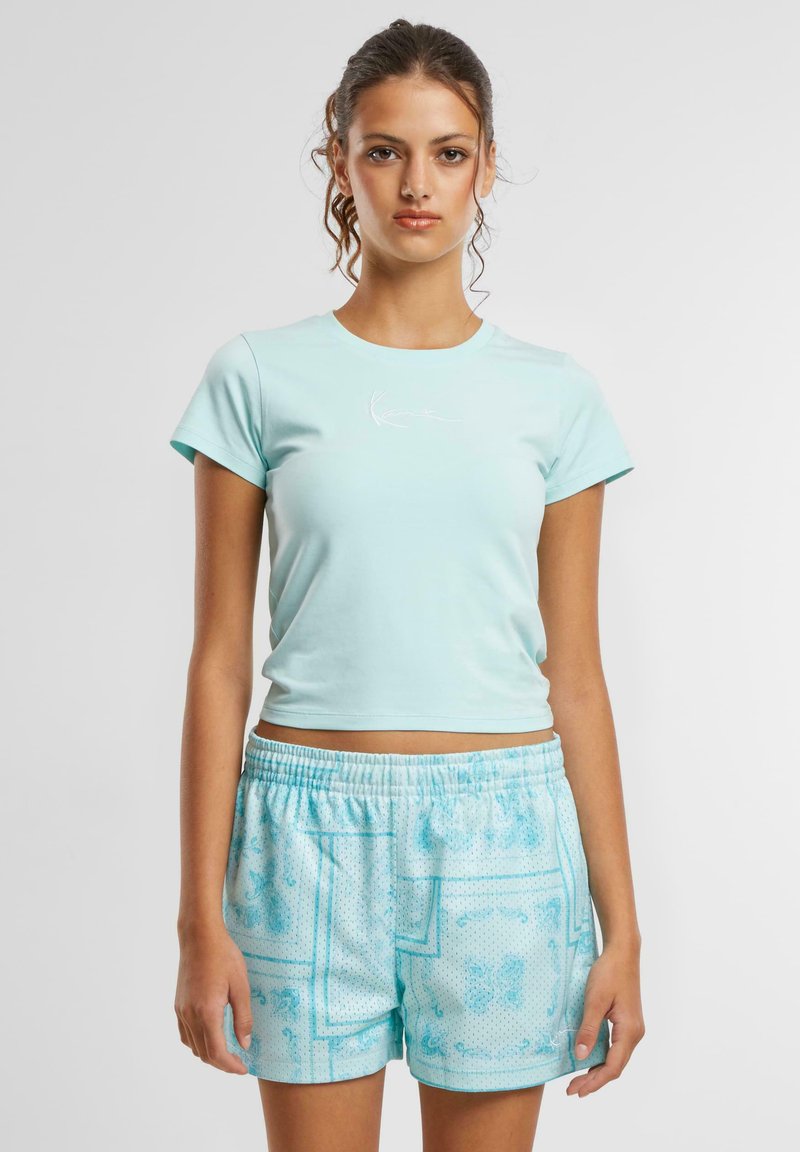 Lys blå kort t-skjorte med korte ermer og en hvit trykt logo, kombinert med mønstrede lys blå shorts med elastisk linning.