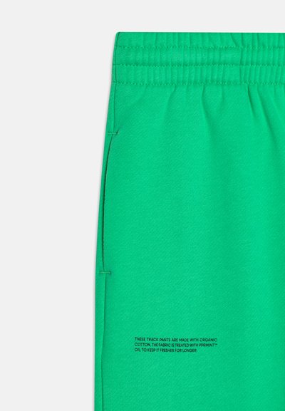 Pantalones deportivos verdes hechos de algodón orgánico, con una cintura ajustable con cordón y bolsillos laterales. El texto en la tela menciona un tratamiento para la frescura.