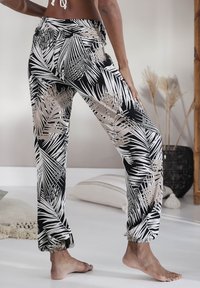 Zwart-witte lichtgewicht broek met palmbladpatroon en een gathered enkeldesign, voorzien van een elastische tailleband en een casual pasvorm.