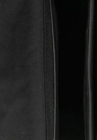 Primo piano di una borsa o giacca in tessuto nero parzialmente aperta, che mostra cuciture lisce lungo il bordo della cerniera.