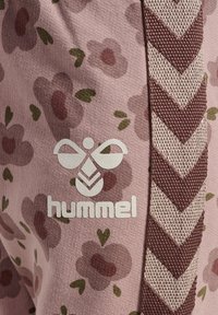 Roze stof met een bloemmotief, featuring bordeaux bloemen en groene bladeren. Hummel-logo in het wit. Zijkant met een chevron ontwerp.