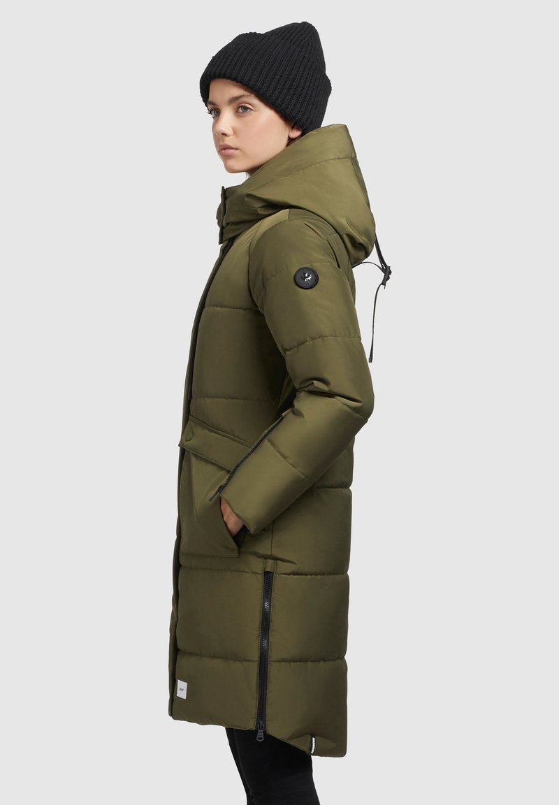 Olivgrüne Daunenjacke mit Kapuze, horizontal gestepptem Design, seitlichen Reißverschlüssen und einem schwarzen Logo-Patch am Ärmel. Trägt eine schwarze Mütze.