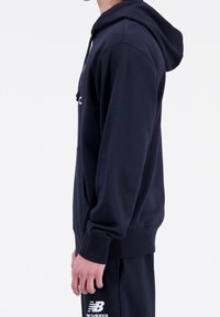 Felpa blu navy realizzata in tessuto misto cotone, con tasca frontale, cappuccio con cordini e logo sul petto. Vista laterale mostrata.