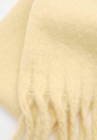 Sciarpa color crema realizzata in morbido tessuto testurizzato con bordi frangiati. Leggera e cade con grazia.