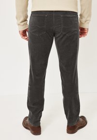 Dunkelgraue Cordhosen, gerade geschnitten, mit zwei Gesäßtaschen und feiner Struktur. Kombiniert mit braunen Lederschuhen.