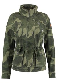 Maskáčová bunda vyrobená z texturované zelené tkaniny s vysokým límcem, zapínáním na zip, knoflíkovými detaily a stahováním v pase. Obsahuje dvě přední kapsy.