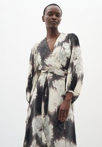 Rochie de tip wrap din material cu un model; caracterizată prin tonuri de negru, alb și gri estompat. Mâneci lungi și cordon ajustabil la talie. Textură netedă și fluidă.