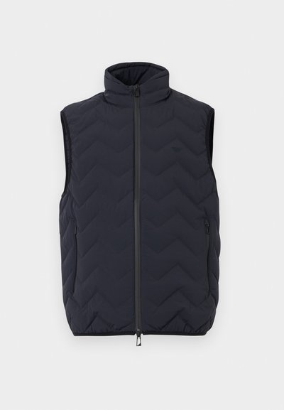 Μαύρο γιλέκο χωρίς μανίκια με ταπιετέ, ψηλό γιακά, φερμουάρ μπροστά και δύο πλαϊνές τσέπες με φερμουάρ.