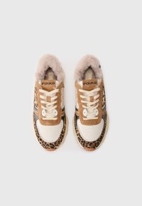 Sneaker con una toma in camoscio color nocciola, dettagli con stampa leopardata, pelle color crema e colletto in pelliccia sintetica. Presenta lacci bianchi e strisce nere.