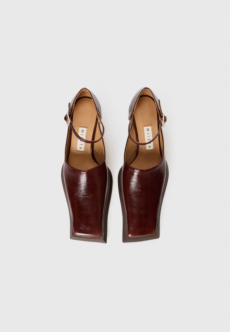 Pair of dark brown leather Mary Jane shoes with square toes and ankle straps, photographed from above on a white background.
