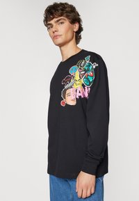 T-shirt nera a maniche lunghe con stampe grafiche colorate, tra cui volti e simboli, realizzata in un morbido misto cotone.