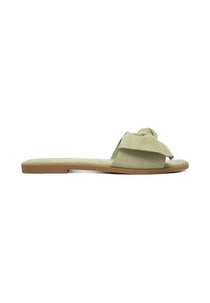 Flache olivgrüne Wildleder-Sandale mit breitem geknotetem Riemen und brauner Sohle, von der Seite vor weißem Hintergrund gezeigt.