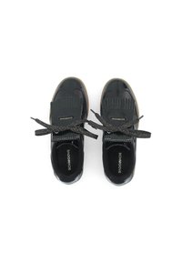 Black patent leather shoes with fringed accents, glitter laces, and a textured sole, featuring a cushioned insole and logo.
