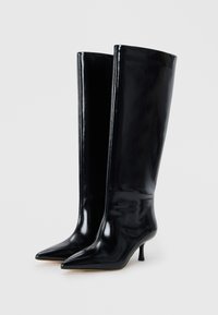 Stivali neri al ginocchio in pelle lucida. Presentano una punta affusolata e un tacco a stiletto, con un design liscio e slanciato.