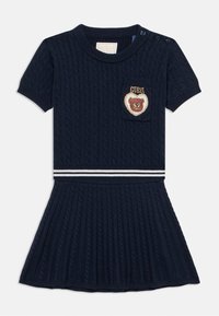 Φόρεμα πλεκτό με καλώδιο σε ναυτικό μπλε, με κοντά μανίκια, μικρή τσέπη και κεντητό σχέδιο αρκούδας. Οριζόντια λευκή ριγέ ζώνη στη μέση.