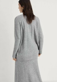 Maglione grigio lavorato a maglia con vestibilità rilassata, caratterizzato da un orlo a coste e maniche lunghe, realizzato in tessuto morbido e dalla texture piacevole.
