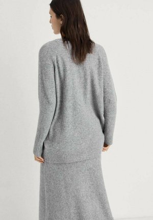 Pull en tricot gris à coupe décontractée, avec un ourlet côtelé et des manches longues, fabriqué en tissu doux et texturé.
