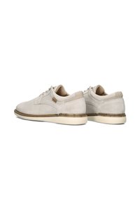 Beige suède schoenen met een textuurafwerking, gedempte accenten, ronde veters en een contrasterende zool hebben een subtiele patronenrand rondom de basis.