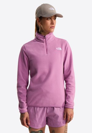 Světle růžová flísová mikina s vysokým límcem a zipem, doplněná o sladěné šortky. Na hrudi je malý bílý logo.