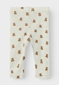 Leggings pour bébé de couleur crème avec un imprimé général de petits ours en peluche marron, présentés à plat sur un fond blanc.
