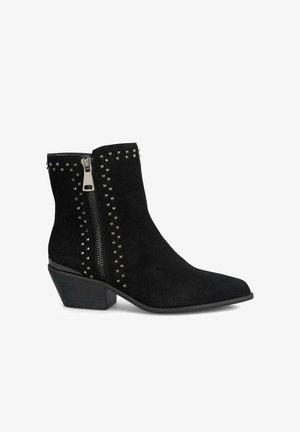 Czarne zamszowe botki za kostkę z wydłużonym noskiem, bocznym zamkiem błyskawicznym i metalowymi ćwiekami wzdłuż szwów. Niski obcas w kształcie bloku o gładkim, wypolerowanym wykończeniu.