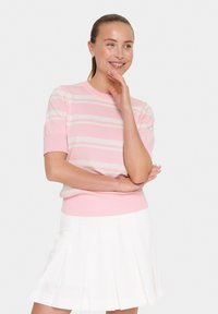 Suéter de punto rosa claro con rayas blancas, de manga corta y puños acanalados. Combinado con una falda blanca plisada.